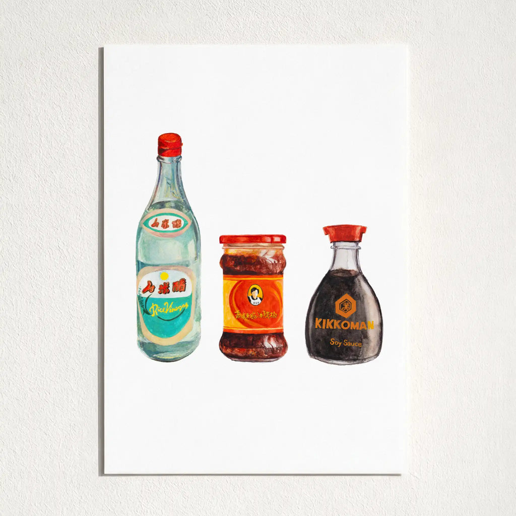 A vertical art print featuring a watercolor-style illustration of three bottles: a light blue bottle with a red cap, a red-labeled jar, and a dark brown Kikkoman soy sauce bottle with a red cap, all on a white background. The print is mounted on a textured light gray wall.