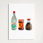 A vertical art print featuring a watercolor-style illustration of three bottles: a light blue bottle with a red cap, a red-labeled jar, and a dark brown Kikkoman soy sauce bottle with a red cap, all on a white background. The print is mounted on a textured light gray wall.
