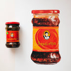 Two jars of a spicy chili product with red labels on a white background