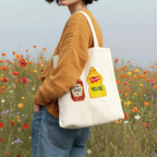 french's yellow mustard watercolor cotton tote bag, shown on model in a flower field