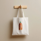 White tote bag with a sriracha bottle design hanging on a wooden hook against a beige wall.